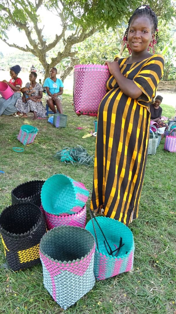 A pregnant teenager smiles while holding a handmade woven bag.