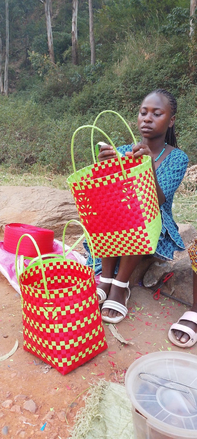 Biira stands beside her basket weaving work and pancake business.