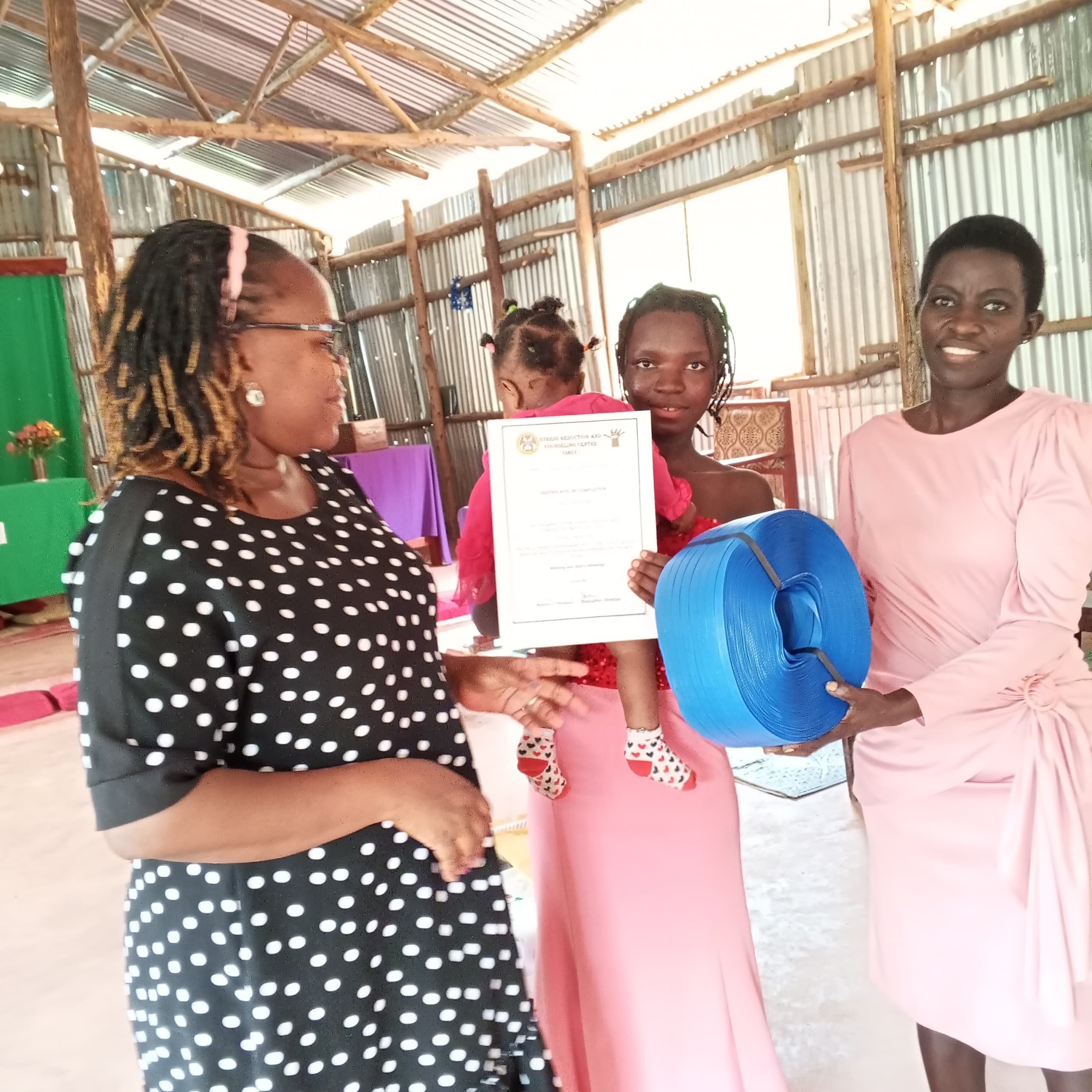 A teenage mother receives a startup kit and certificate after completing training.